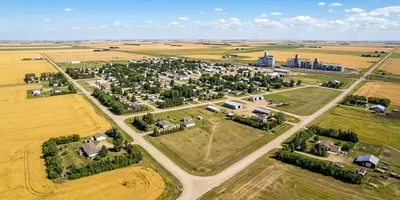 Aerial view of a Jansen Region prairie town in summer with grain elevators and golden wheat fields