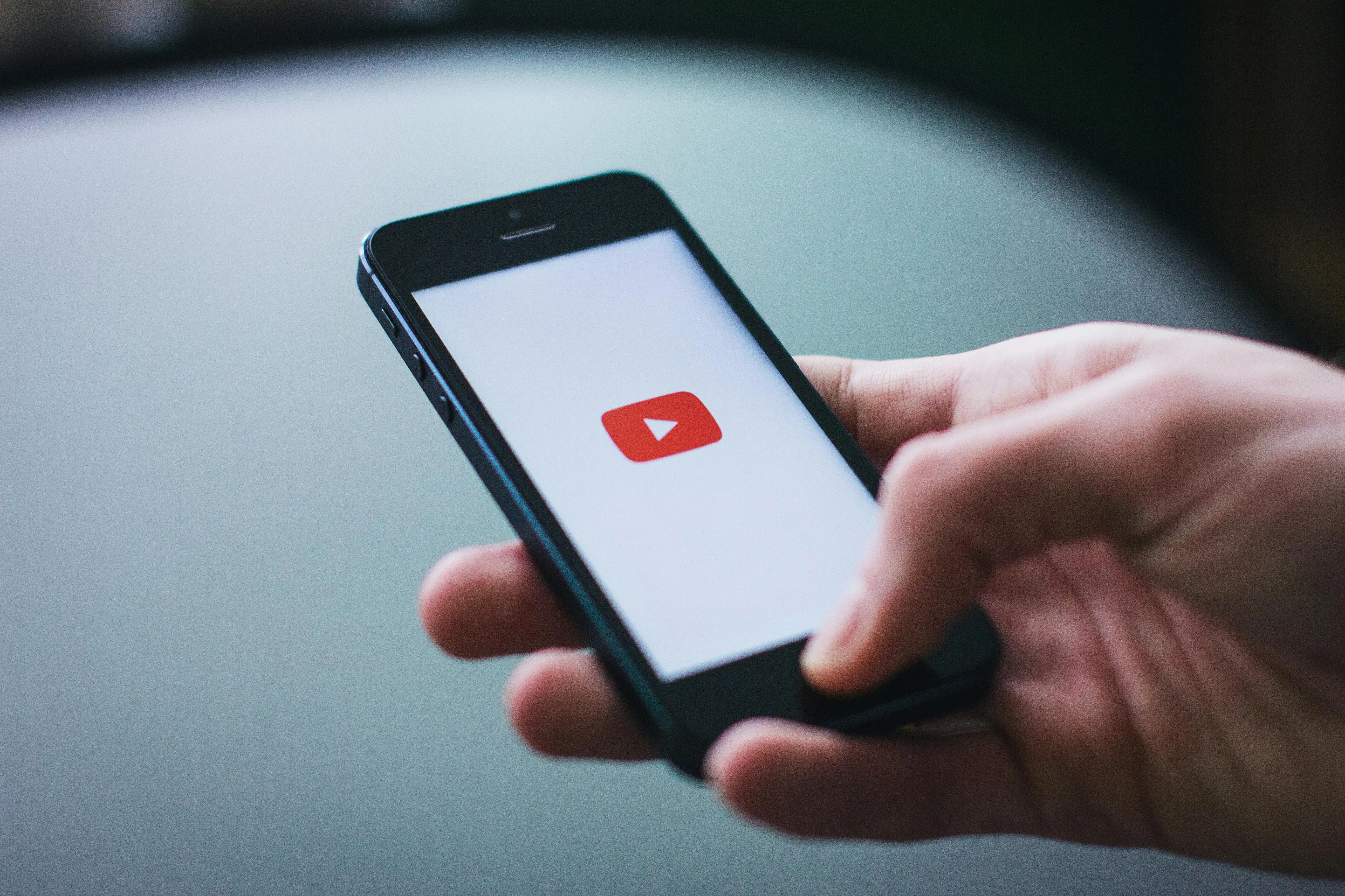 Hand holding a phone with the youtube logo on it