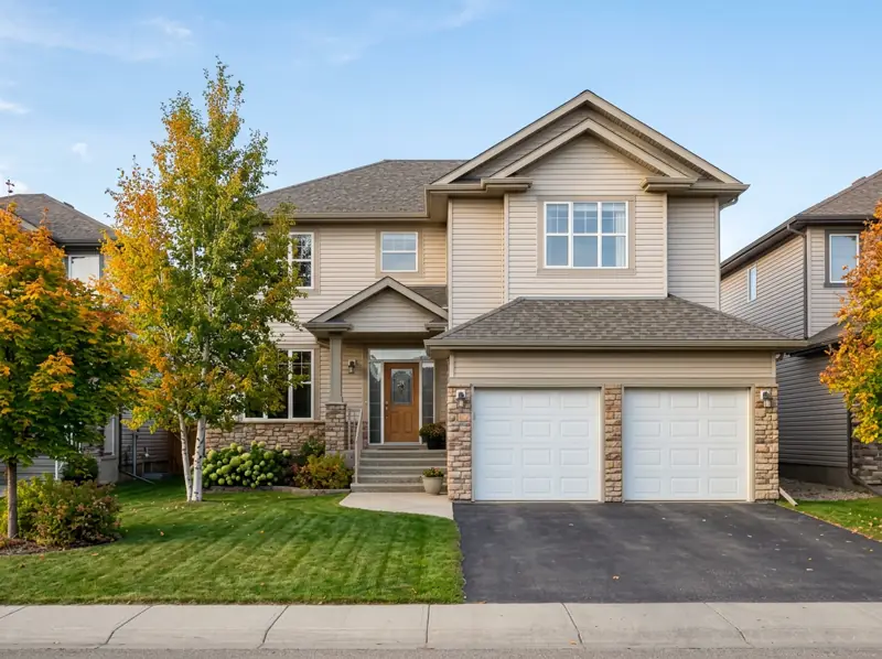 Early-2000s two-storey home with an attached garage and fall trees on an Arbor Creek street
