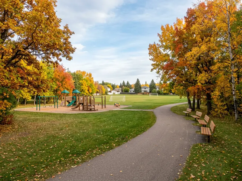 Brevoort Park playground, sports field and fall shade trees along a paved path in Saskatoon