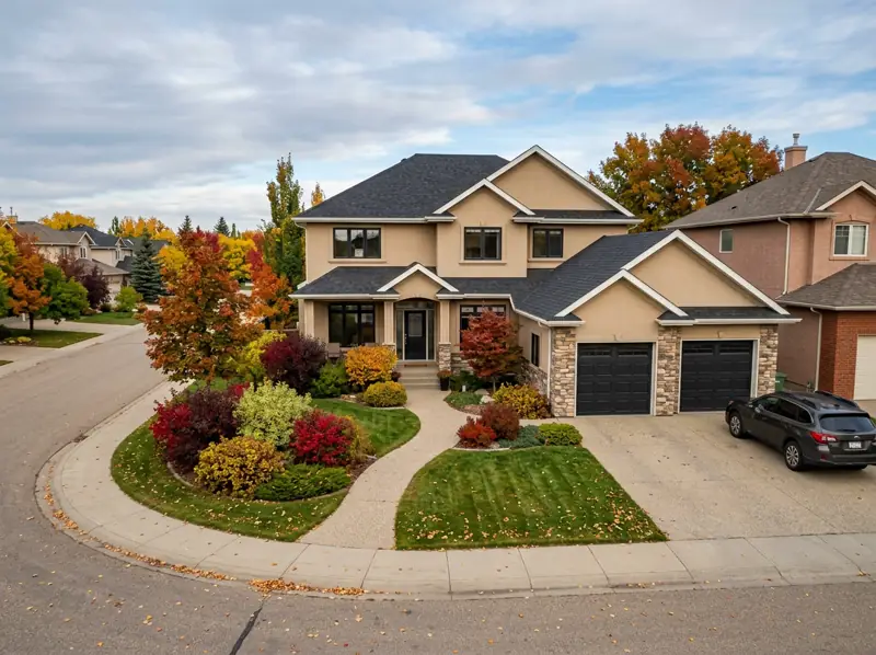 2000s two-storey stucco home with double garage and fall landscaping on a Briarwood crescent, Saskatoon