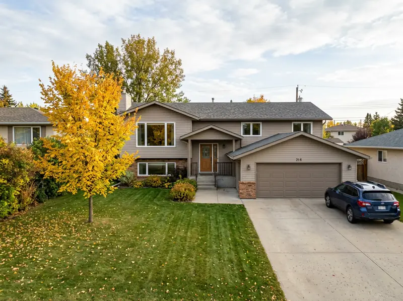 1980s bi-level home with an attached garage and a gold fall tree on a large lot in Dundonald