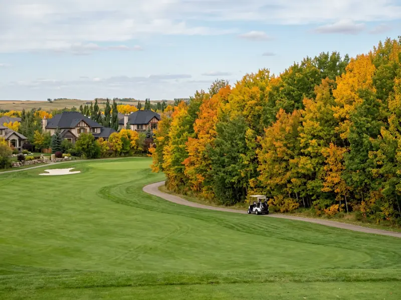 Golf course fairway lined with yellow and orange fall trees next to homes in East College Park
