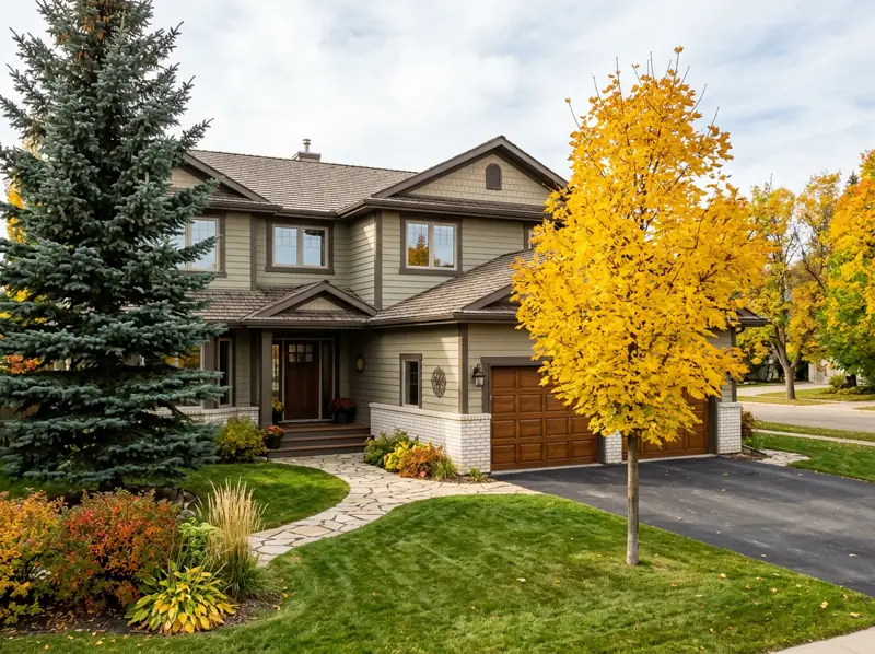 1980s two-storey detached home with attached garage and fall trees in Erindale, Saskatoon