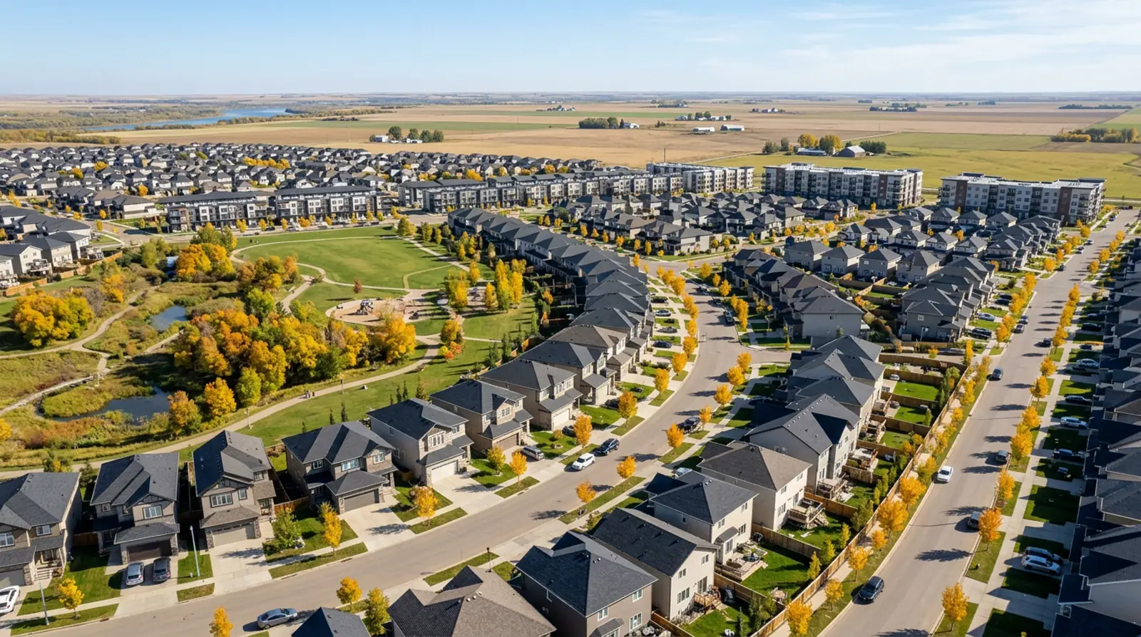 Aerial view of 2010s two-storey homes, townhouses and young fall trees in Evergreen, Saskatoon