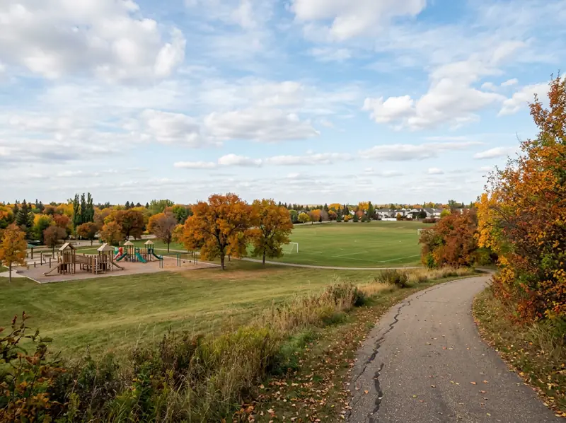 Open park with sports field, playground and fall trees in Fairhaven, Saskatoon