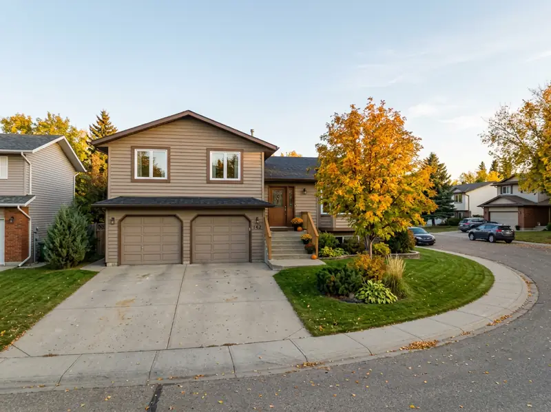1980s bi-level home with an attached double garage and a golden fall tree in Lakeridge