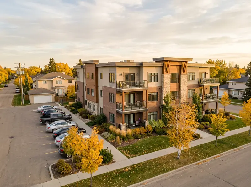 Low-rise condo building with balconies next to detached homes under fall trees in Lakewood