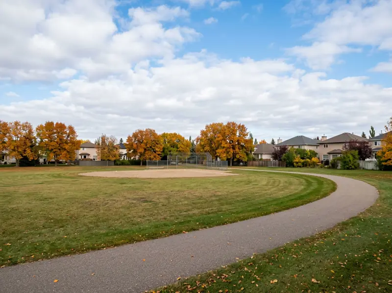 Montgomery Place Saskatoon park with ball diamond, open grass and orange fall trees beside homes