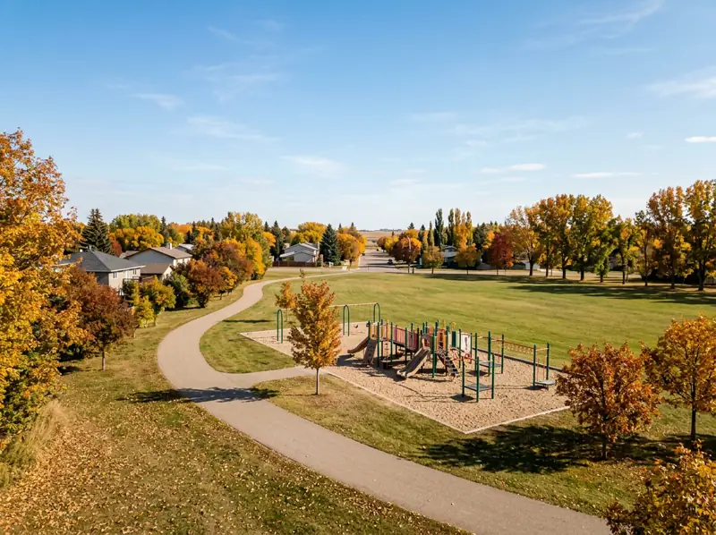 Mount Royal Saskatoon park with playground, sports field and paved path under fall trees