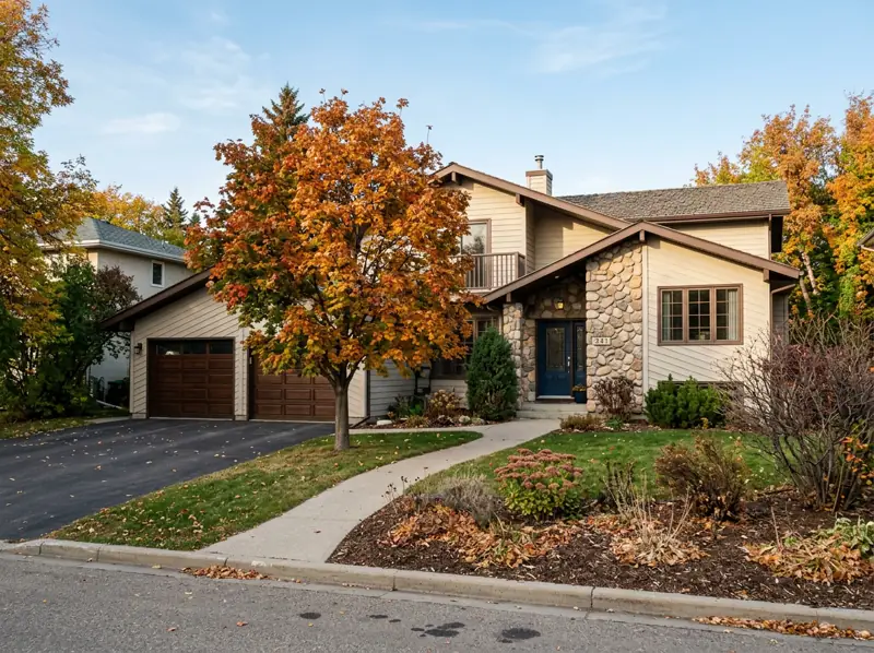 1980s split-level house with attached double garage and an orange fall tree in Parkridge, Saskatoon