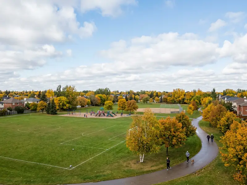 Open sports field, ball diamond and tree-lined path in fall colours at a Silverspring park