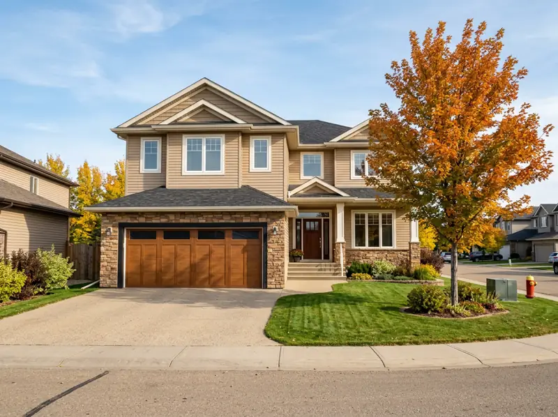 2000s two-storey home with stone accents, double garage and an orange fall tree in University Heights